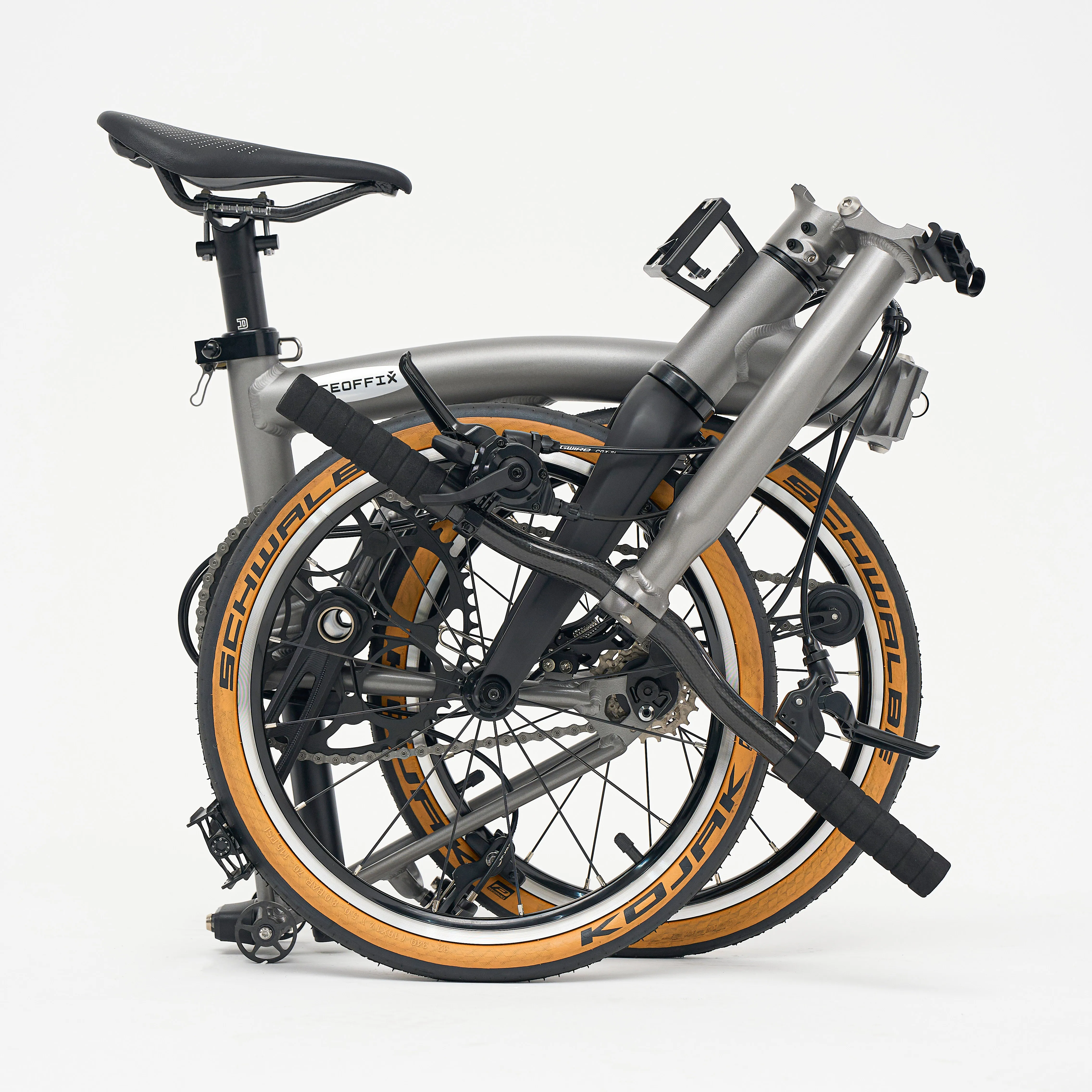 Aerra folding bike in the folded position, Titanium Grey frame with Schwalbe Kojak tan-wall tyres — rear three-quarter view
