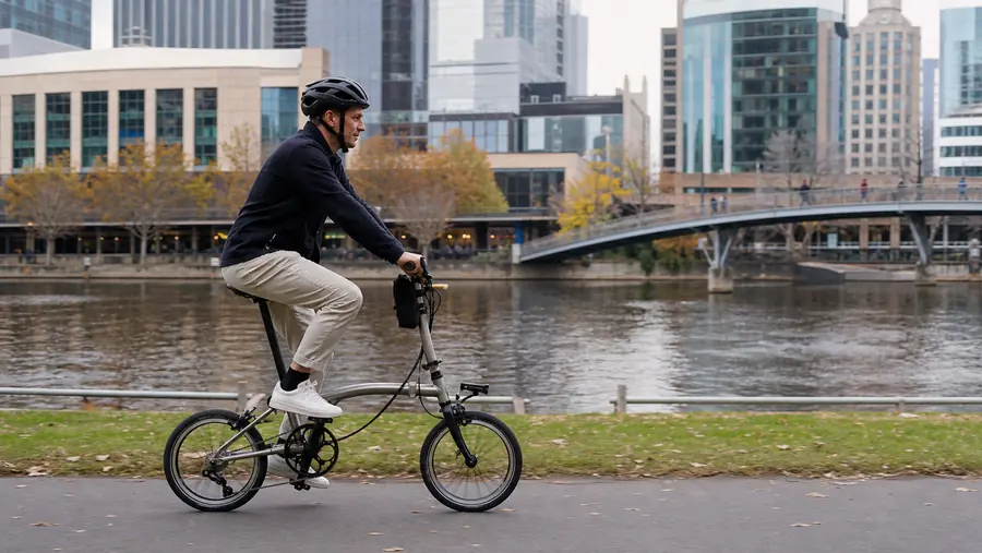 A rider on the Capital City Trail next to the Yarra, autumn city skyline in the distance.